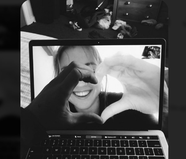 Couple making a heart shape together on a laptop video call