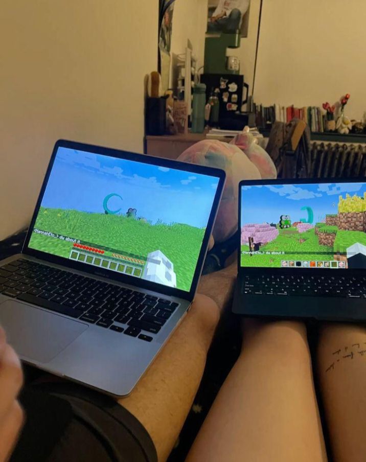 Couple playing Minecraft together on laptops side by side